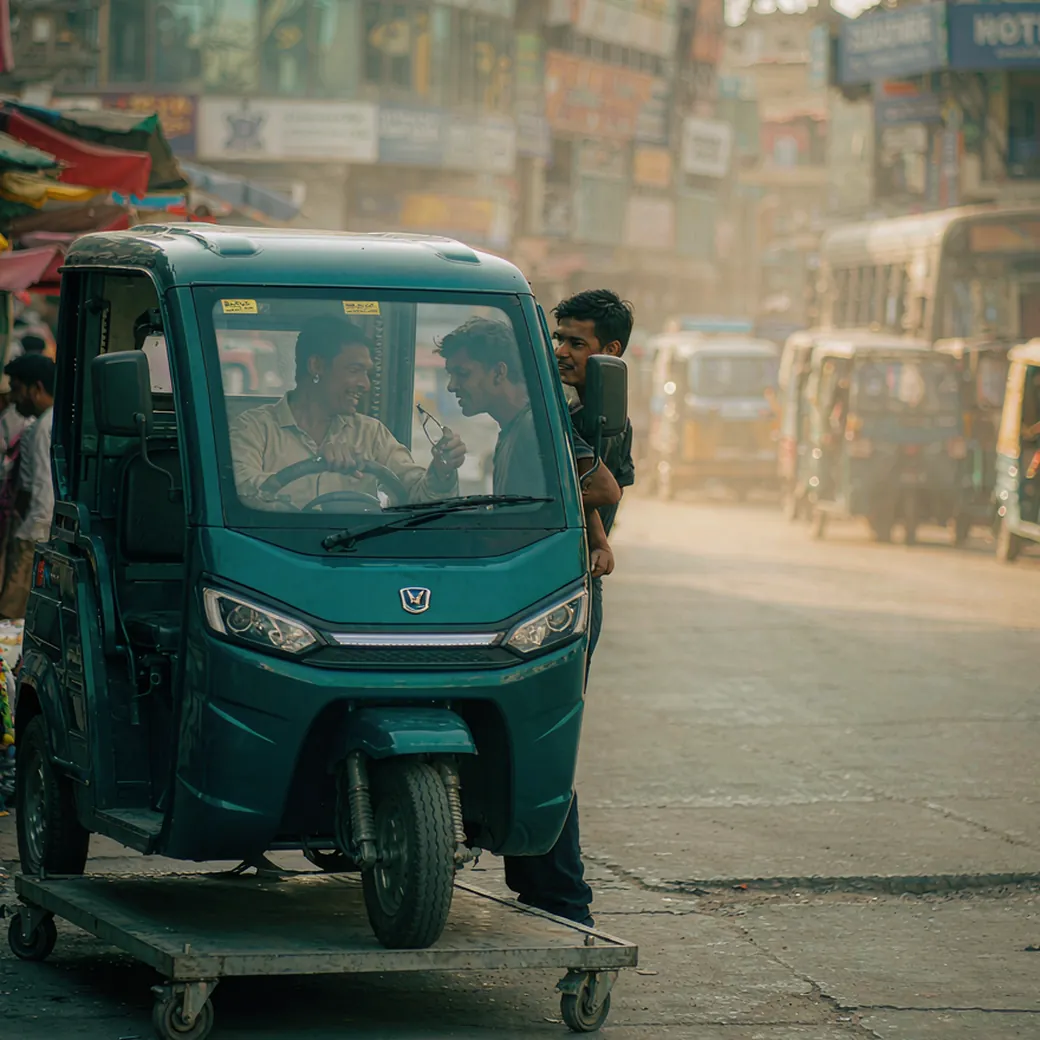 A new electric auto-rickshaw at a Dhaka street corner, driver taking passengers at golden hour